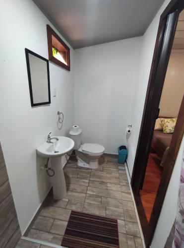 a bathroom with a toilet and a sink at House in the palm forest in Carrillo