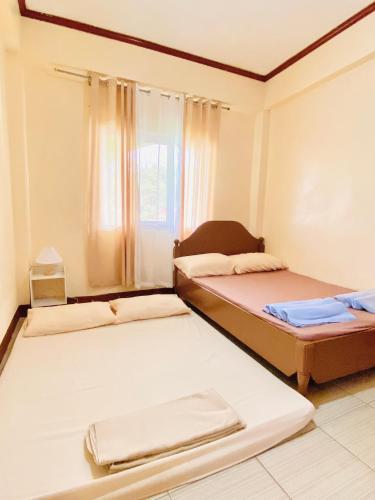 twee bedden in een kamer met een raam bij Unit Three Transient Home in Baguio
