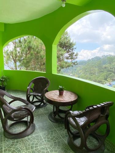 drie stoelen en een tafel in een kamer met groene muren bij Unit Three Transient Home in Baguio