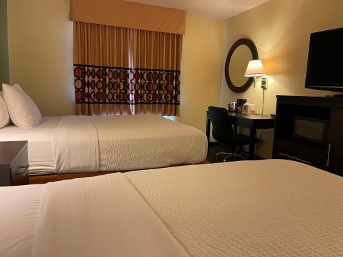a hotel room with two beds and a desk with a mirror at Super 8 by Wyndham Colby in Colby