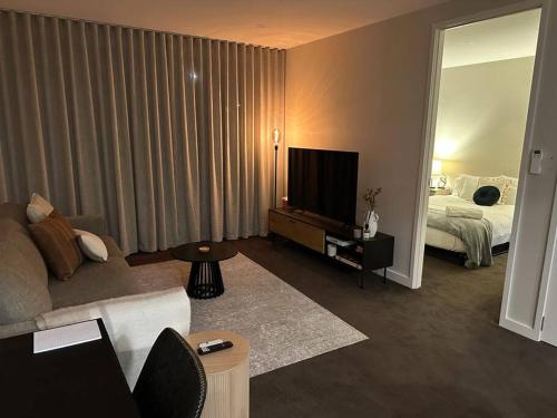sala de estar con sofá, TV y cama en Modern Griffith Apartment, en Kingston 