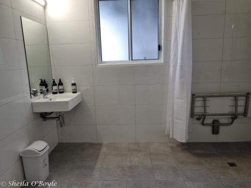 a white bathroom with a sink and a mirror at Glen Lough Cabins in Glen Aplin