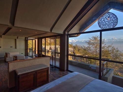 a bedroom with a bed and large glass windows at Kavya Resort & Spa in Nagarkot
