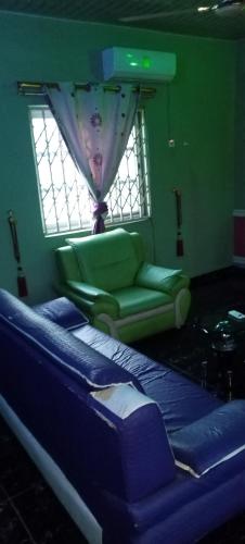 a room with a bed and a couch and a window at Executive Lodge in Kasoa