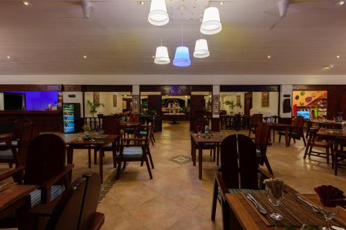 a restaurant with wooden tables and chairs in a room at Hotel Cote d'or Lodge in Baie Sainte Anne