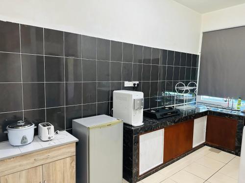 a kitchen with a refrigerator and a counter top at Macagawa Homestay in Tawau