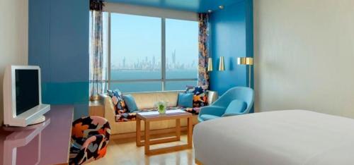 a room with a bed and a couch and a tv at Symphony Style Hotel Kuwait in Kuwait