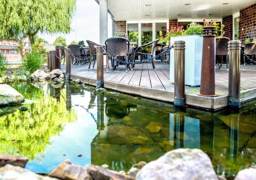 a pond with chairs and tables on a patio at Hotel Hilling in Papenburg