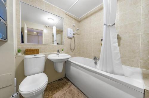 a bathroom with a toilet and a tub and a sink at London flat next to DLR station with free parking in London