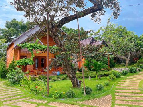 ein Holzhaus mit einem Baum im Hof in der Unterkunft SORA HOMESTAY in Pleiku