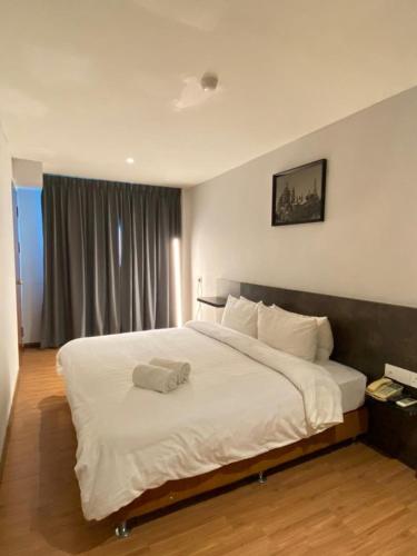 um quarto com uma grande cama branca com almofadas brancas em Express Inn Bintulu em Bintulu