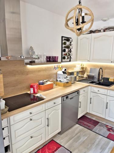 une cuisine avec des armoires blanches et un lustre dans l'établissement Villa Confort Jacuzzi Barbecue Clim Parking, à Marseille