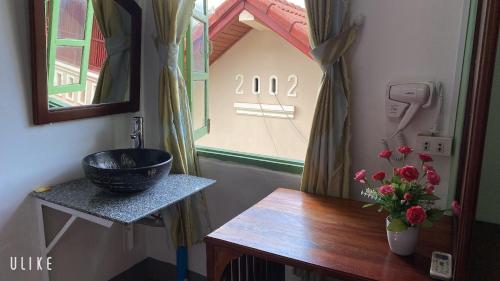 ein Badezimmer mit einem Waschbecken und einer Vase aus Blumen auf dem Tisch in der Unterkunft Villa Thavisouk Legend - Luang Prabang in Luang Prabang