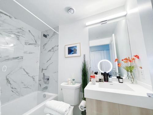 ein weißes Badezimmer mit einer weißen Badewanne und einem Waschbecken in der Unterkunft Boutique Penthouse-Live in the SKY with Amazing Lakeview! Downtown Toronto!B in Toronto
