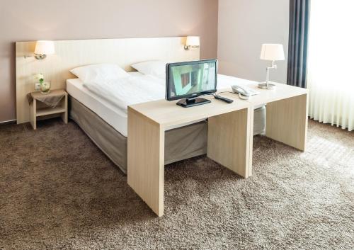 a bedroom with a bed with a desk with a computer on it at Hotel Hilling in Papenburg