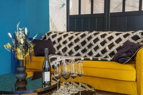 - un canapé jaune avec une table et des verres à vin dans l'établissement Le Baleschoux - PrestiPlace Tours, à Tours
