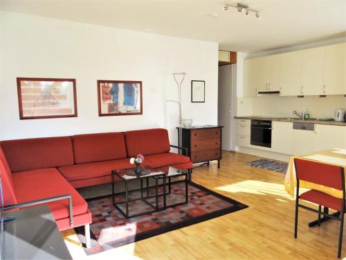 a living room with a red couch and a kitchen at Appartements Margot in Krumpendorf am Wörthersee