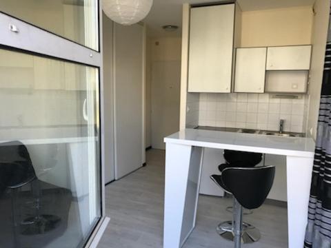 - une cuisine avec des placards blancs et des chaises noires dans l'établissement GRAND STUDIO MER ET PORT DES MINIMES, à La Rochelle