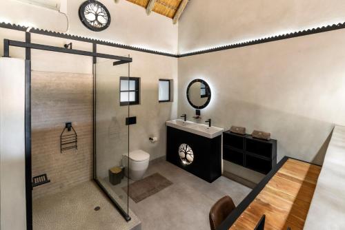 a bathroom with a sink and a shower and a clock at Chobe River Lodge in Kasane