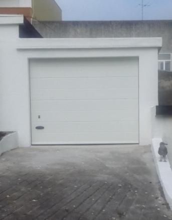a cat sitting next to a large white garage door at Portela - APARTAMENTO in Viana do Castelo