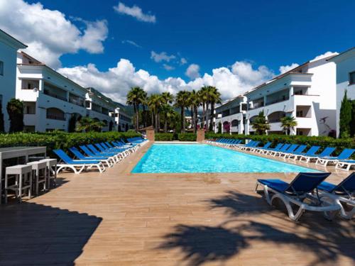una piscina con sedie a sdraio e edifici blu di Vacances en Corse a San-Nicolao