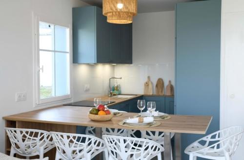 a kitchen with a wooden table and white chairs at Retour de plage in Locmaria