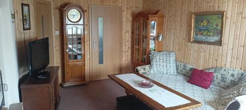 a living room with a couch and a table and a clock at Sunny terrace in Střížov
