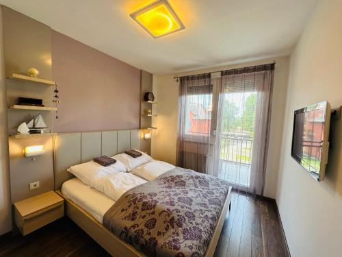 Un dormitorio con una cama grande y una ventana en B13 Apartman Siófok en Siófok