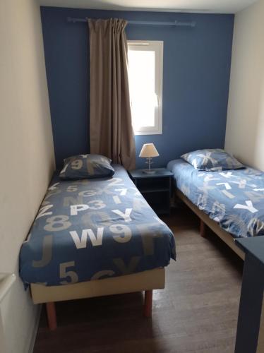 deux lits dans une chambre aux murs bleus dans l'établissement Golf Sauvignon 13, à Lacanau