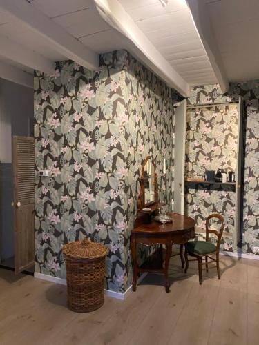 Cette chambre comprend une table et un mur recouvert de fleurs. dans l'établissement La Tuilerie, à Verteuil-sur-Charente