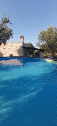 uma piscina com água azul em frente a um edifício em Casale Valle degli Ulivi em Ostuni