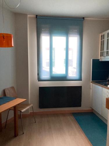 a living room with a window and a table and a kitchen at Alojamientos Maramar in Candás