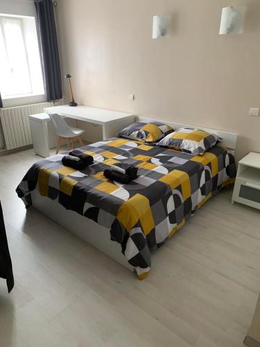 - une chambre avec un grand lit et une couverture jaune et noire dans l'établissement L'hoste dou Lacq, à Lacq