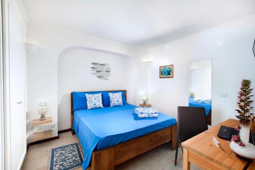 a bedroom with a blue bed and a desk at Faraglionensis MonaconeHouse Apartment in Capri