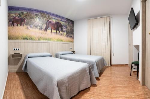 two beds in a room with a painting on the wall at Hostal Viñuela in San Pedro de Mérida