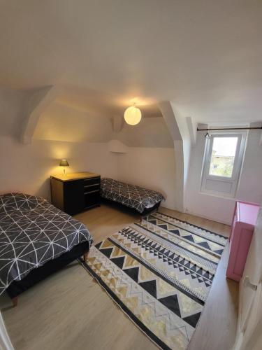 a attic room with two beds and a window at Les écuries du chateau - 5 minutes Circuit des 24 H du MANS - 7 Personnes in Moncé-en-Belin