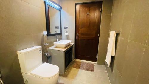 een badkamer met een toilet, een wastafel en een spiegel bij Flamingo Village in Jaffna