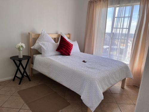 ケンプトンパークにあるOne bedroom cosy apartment in Kempton Parkのベッド(赤と白の枕付)、窓が備わります。