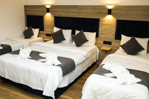 a hotel room with three beds with white sheets at Melissa Suite in Trabzon