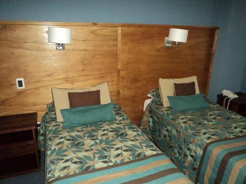 a hotel room with two beds and two lamps at Hotel Tierra del Fuego in Ushuaia