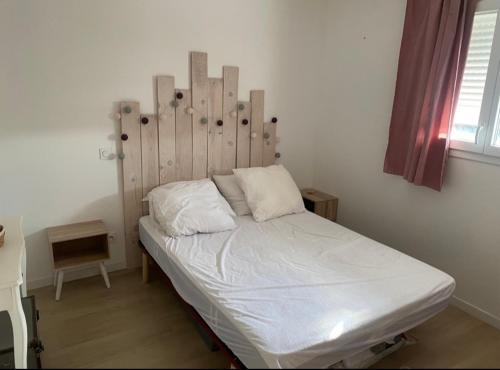 1 cama con cabecero de madera en una habitación en Maison, piscine centreville Gujan-Mestras 4 hôtes, en Gujan-Mestras