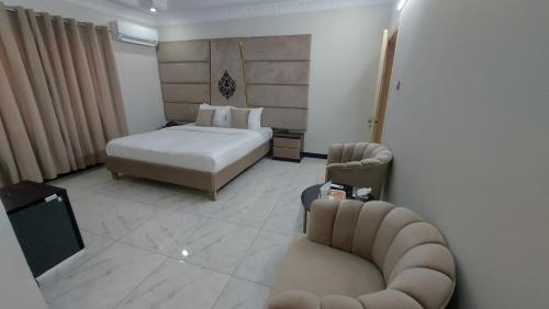 a bedroom with a bed and a couch and chairs at Arena Lodge Guesthouse in Islamabad
