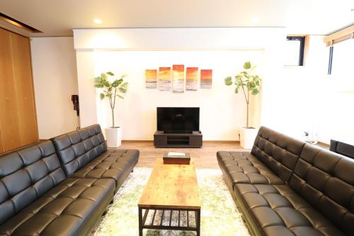 a waiting room with leather couches and a table at Crane Court KitaHorie in Osaka
