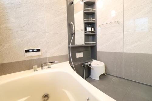 a bathroom with a bath tub and a toilet at Crane Court KitaHorie in Osaka