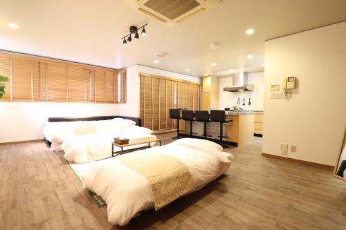two beds in a large room with a kitchen at Crane Court KitaHorie in Osaka