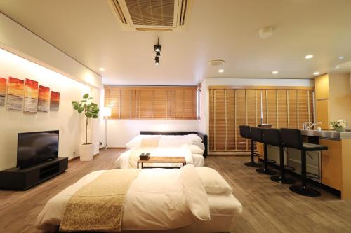 a bedroom with two beds and a desk and a television at Crane Court KitaHorie in Osaka