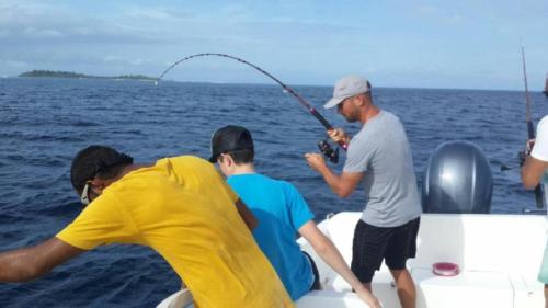 a group of men fishing on a boat in the water at Batuta Maldives Fourson in Thulusdhoo