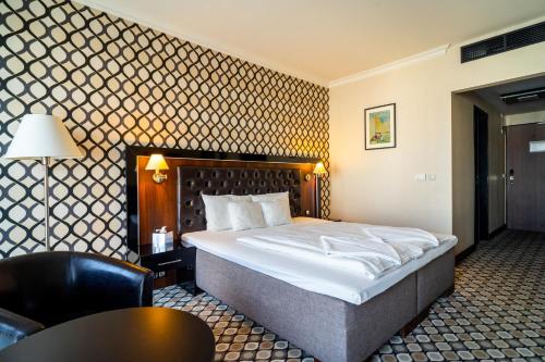 a hotel room with a bed and a chair at Hotel Castello & Thermal Spa Siklós in Siklós