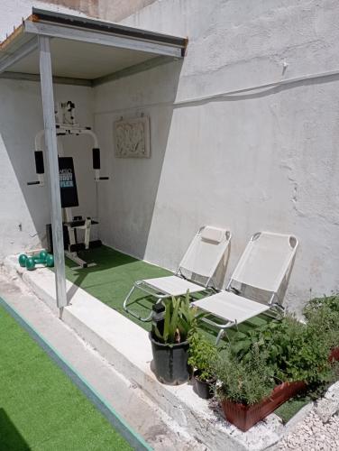 2 chaises longues assises sur une terrasse avec pelouse dans l'établissement CASA VACANZA NONNA EMMA, à Lizzano