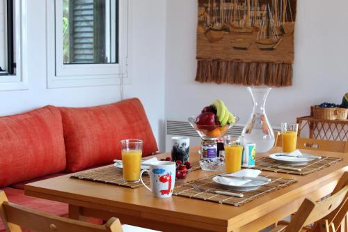 a dining room table with breakfast foods and orange juice at Caper & Olive mountain cottage in Vathí